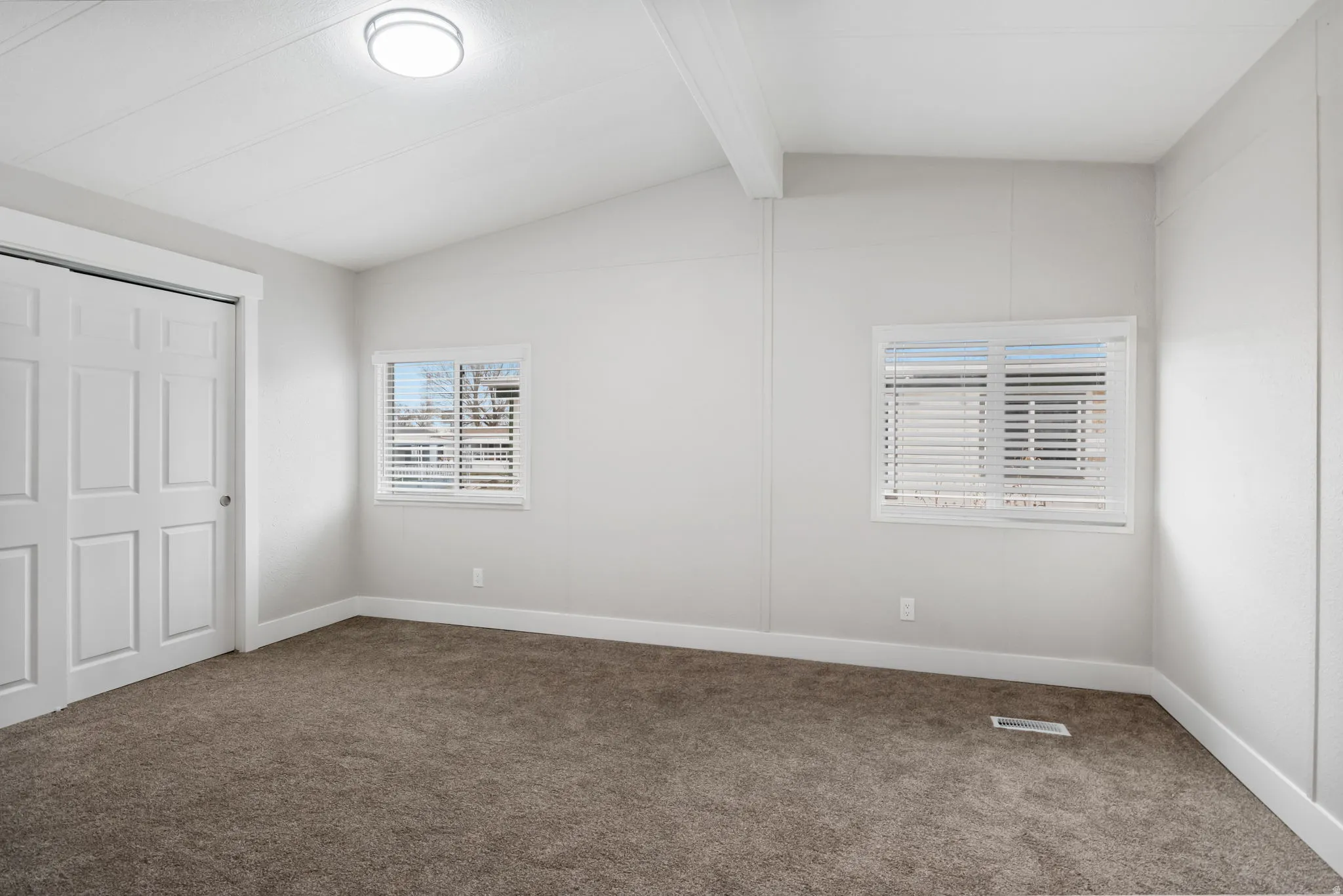 Unfurnished bedroom with carpet, beam ceiling, and a closet