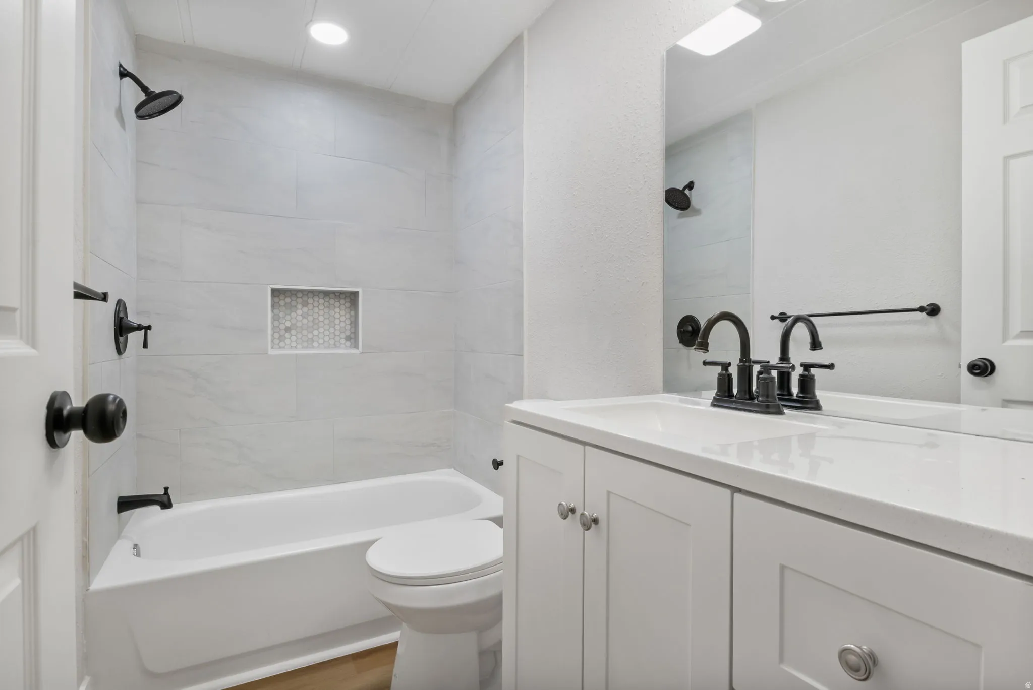 Bathroom featuring shower / washtub combination, vanity, and a textured wall