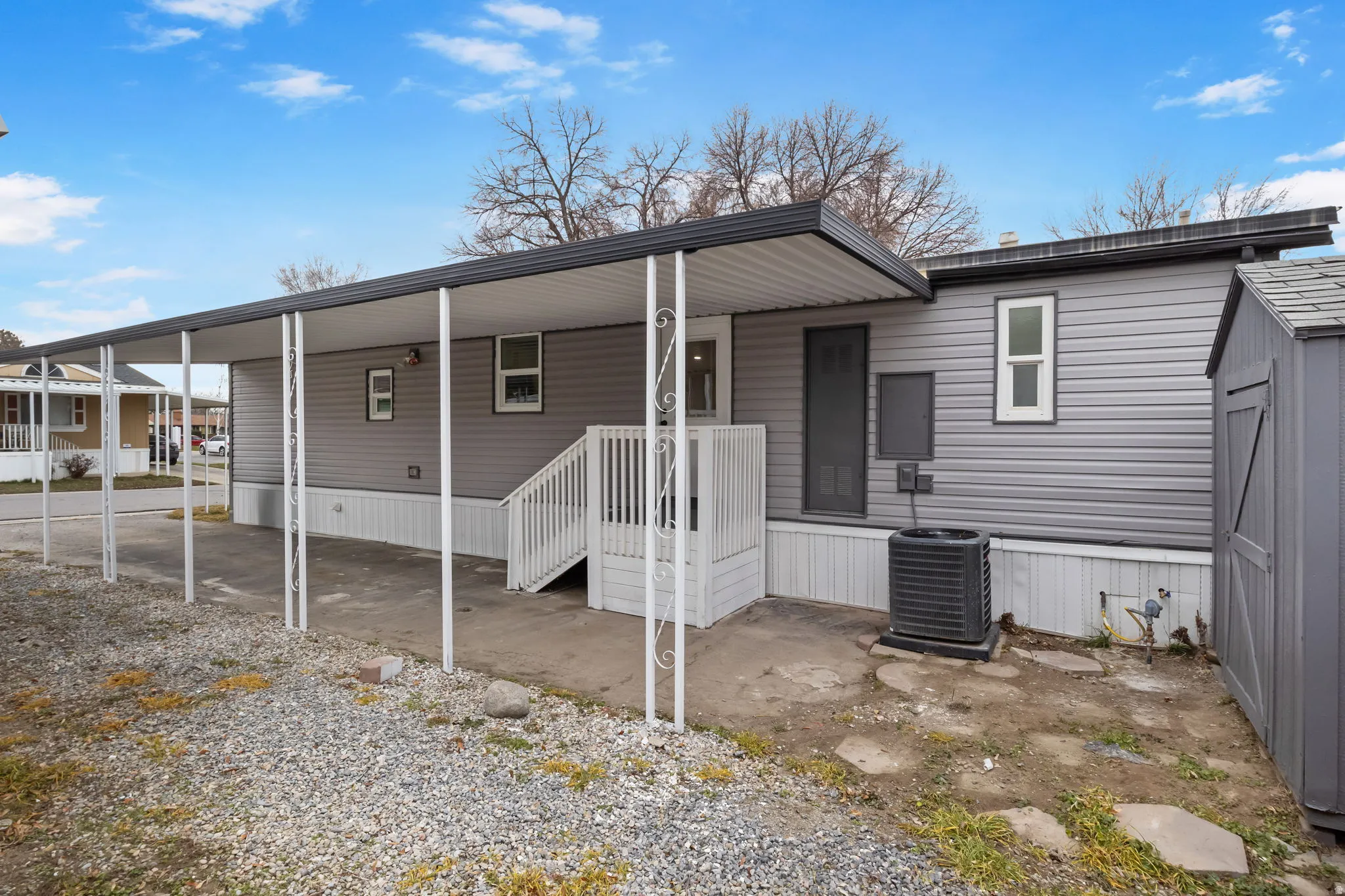Back of property featuring covered porch, an attached carport, and a shed