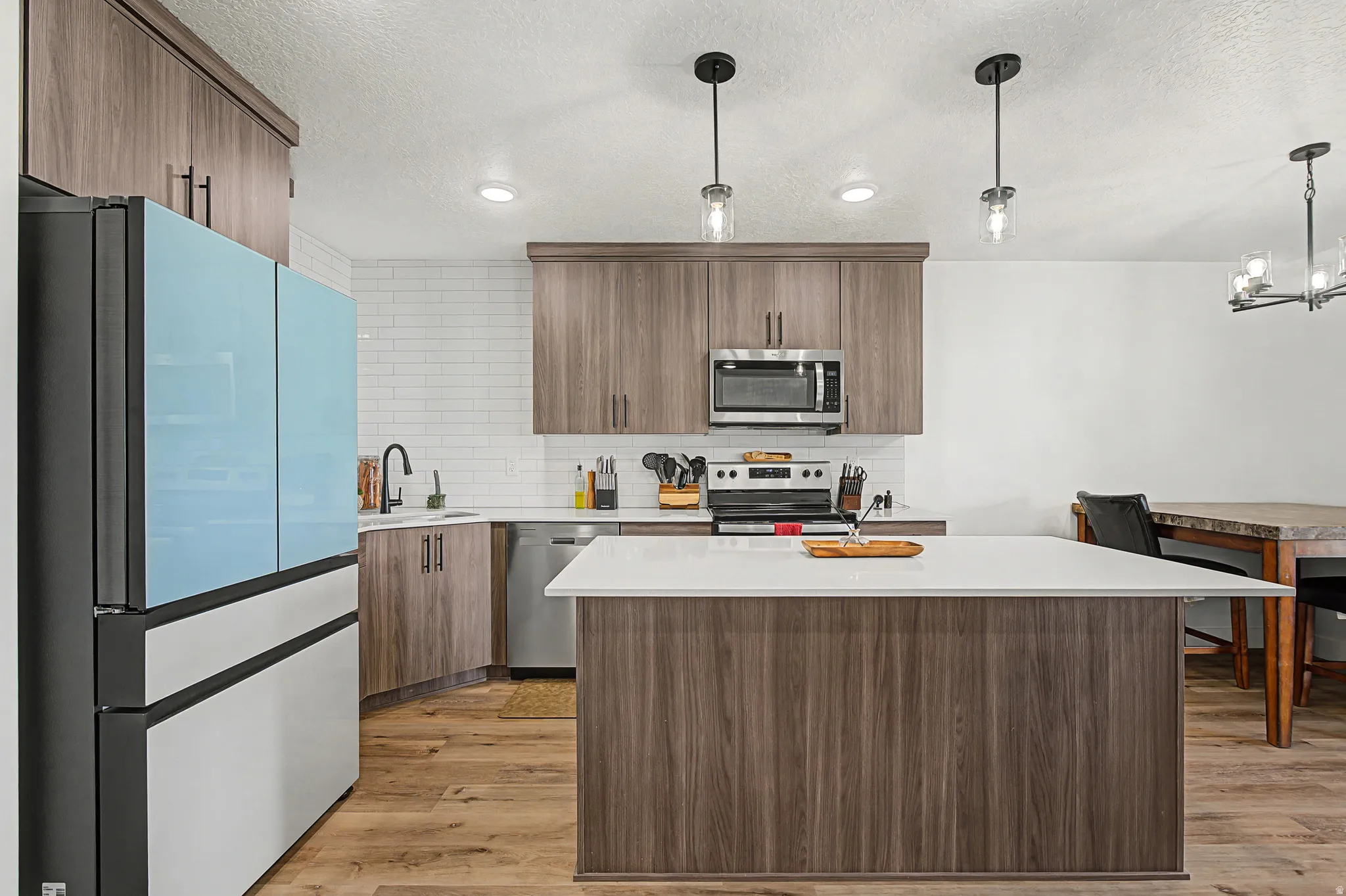 Kitchen with stainless steel appliances, a kitchen island, decorative backsplash, and wood finish cabinetry