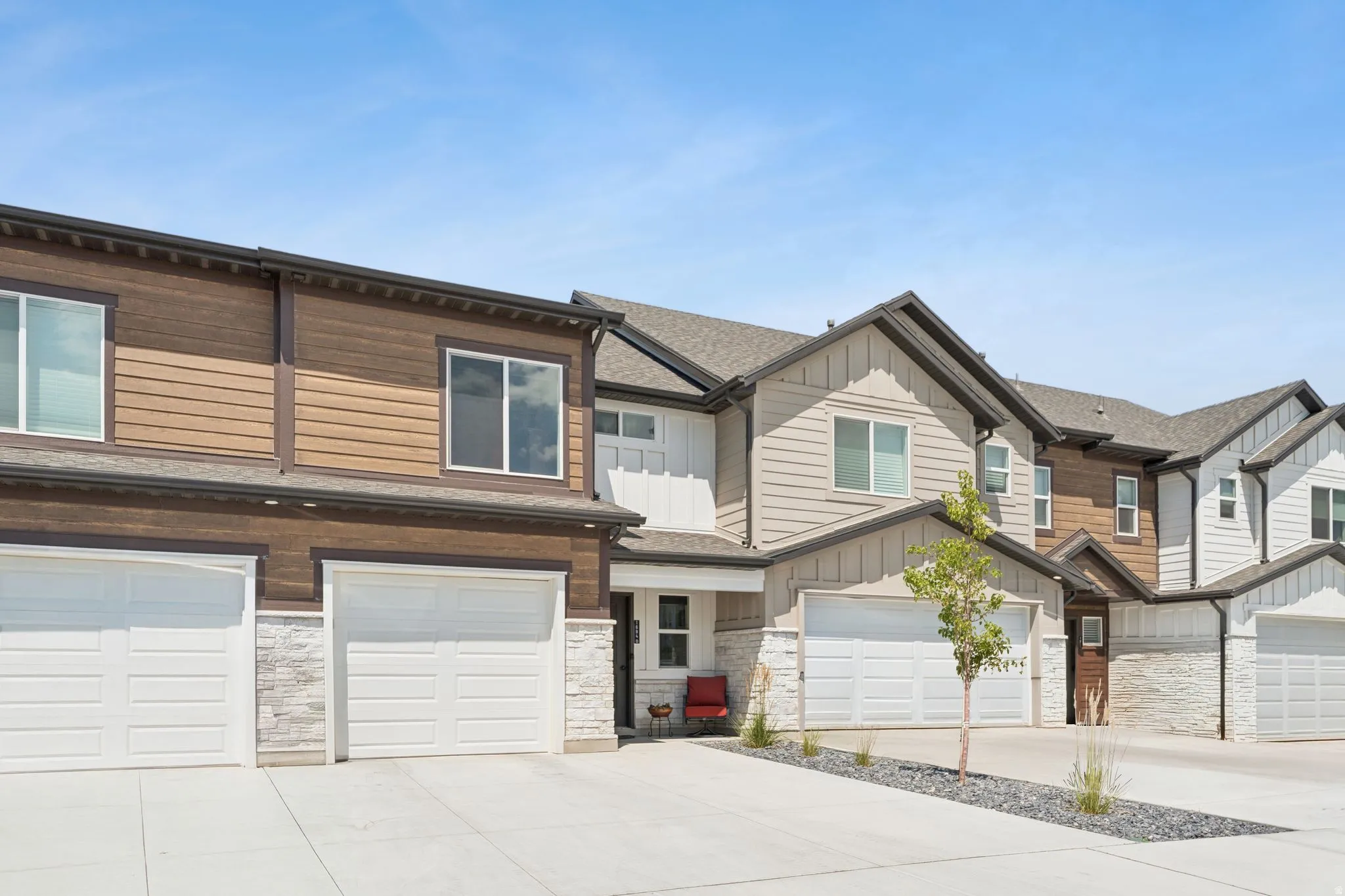 View of front of property with driveway, an attached garage, stone siding, and a shingled roof
