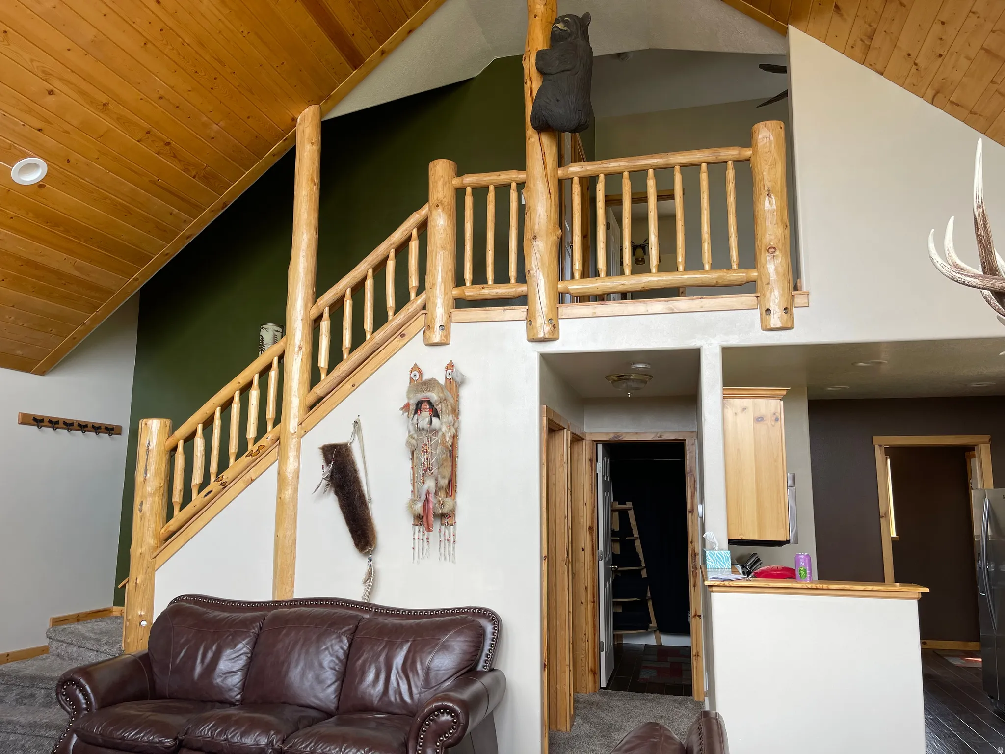 Carpeted living room featuring a vaulted wood ceiling and stairs