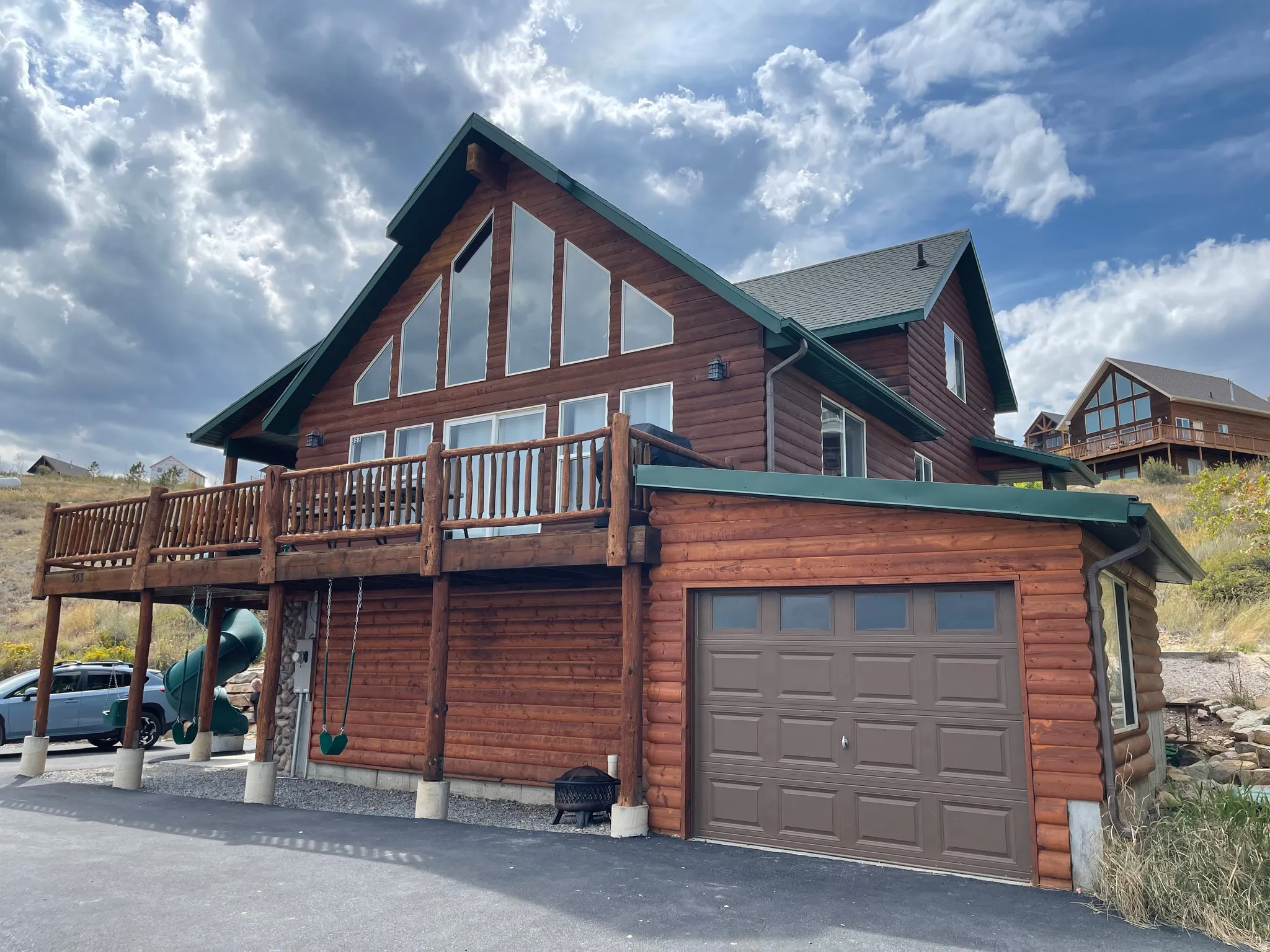 Back of house featuring faux log siding, a deck, and an attached garage