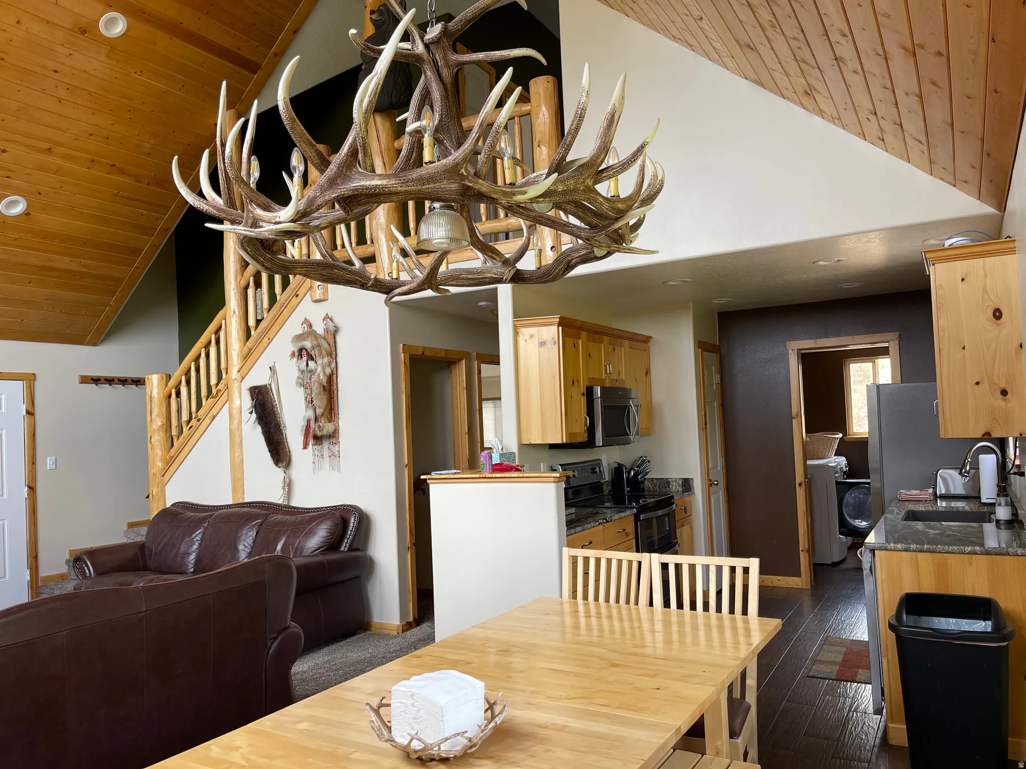 Dining area with a vaulted wooden ceiling, a chandelier, dark wood-type flooring, and washer / dryer