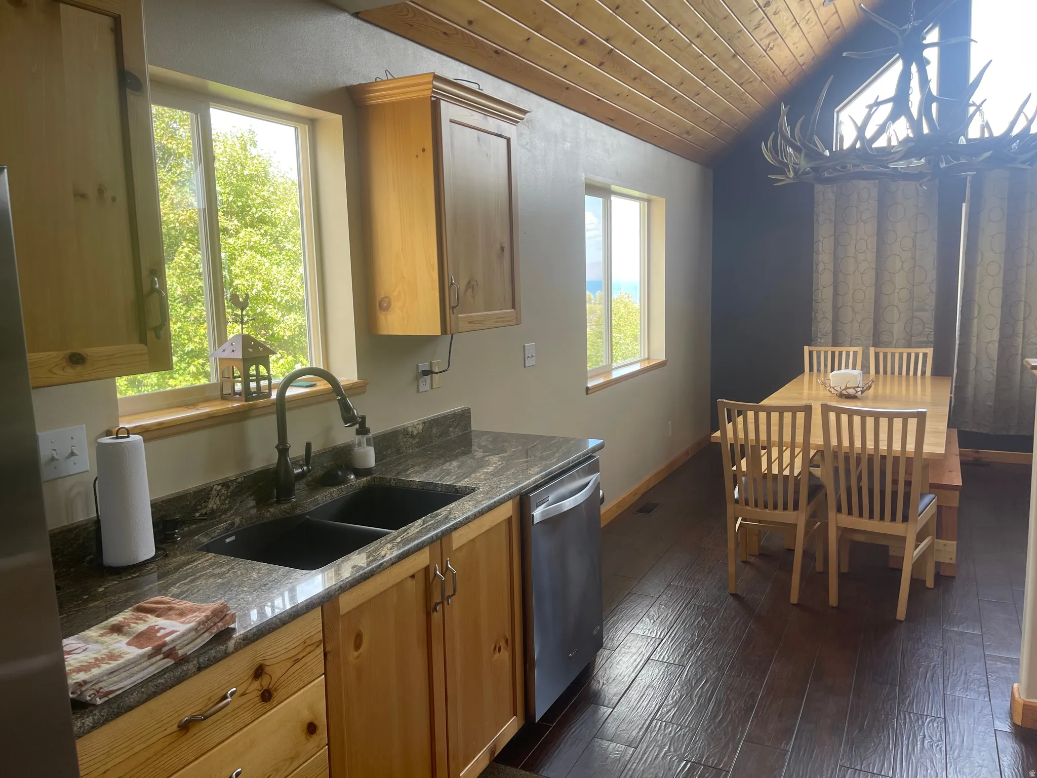 Kitchen featuring a vaulted wooden ceiling, stainless steel appliances, dark wood-type flooring, and dark stone counters