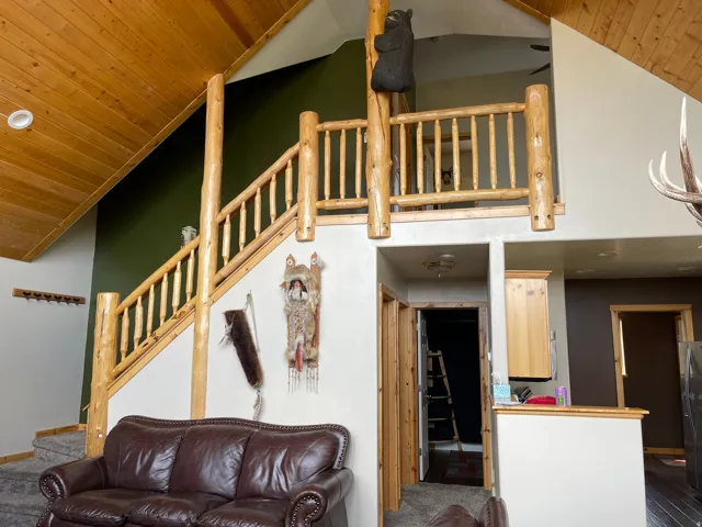 Carpeted living room featuring a vaulted wood ceiling and stairs