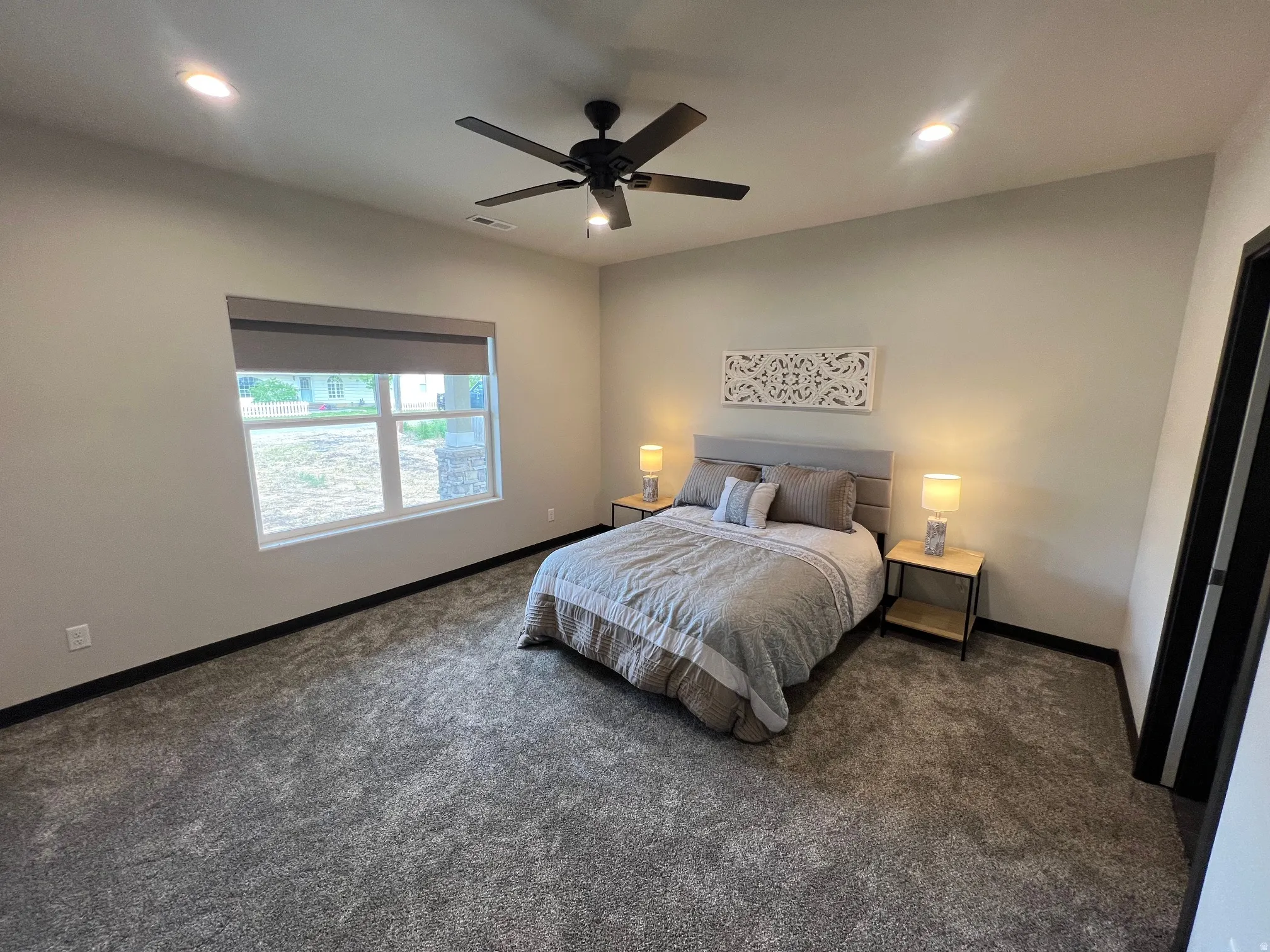 Carpeted room featuring a ceiling fan, recessed lighting, and a large window with a roller shade
