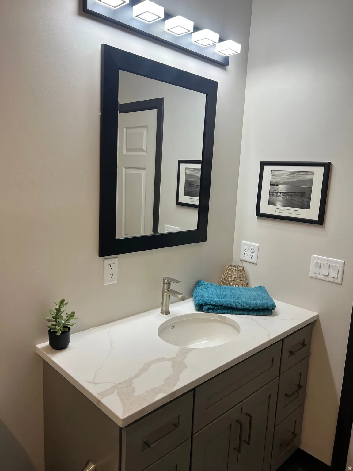 Modern vanity featuring a light-toned countertop with veining, an undermount sink, and a brushed nickel faucet