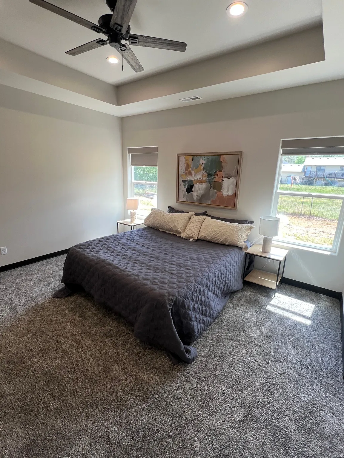 Spacious room featuring a tray ceiling with recessed lighting and a ceiling fan