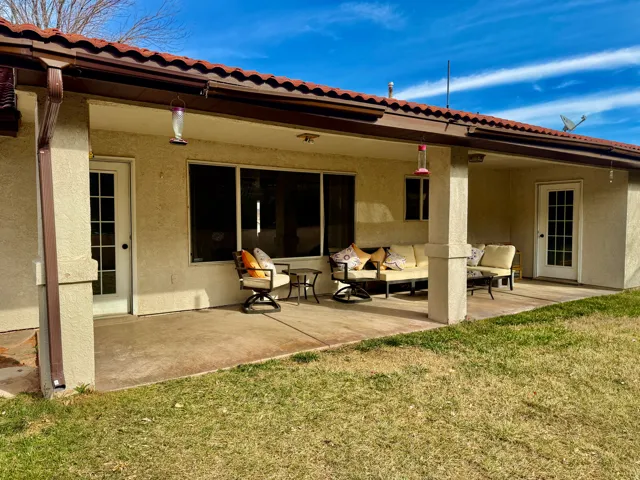 Rear view of house with a patio, a yard, and stucco siding