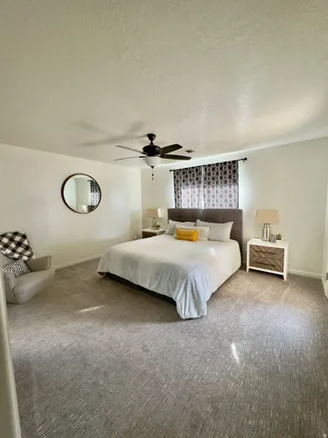 Bedroom with carpet floors, a textured ceiling, and ceiling fan