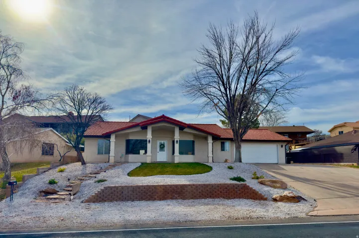Single story home with concrete driveway, stucco siding, an attached garage, and a tiled roof