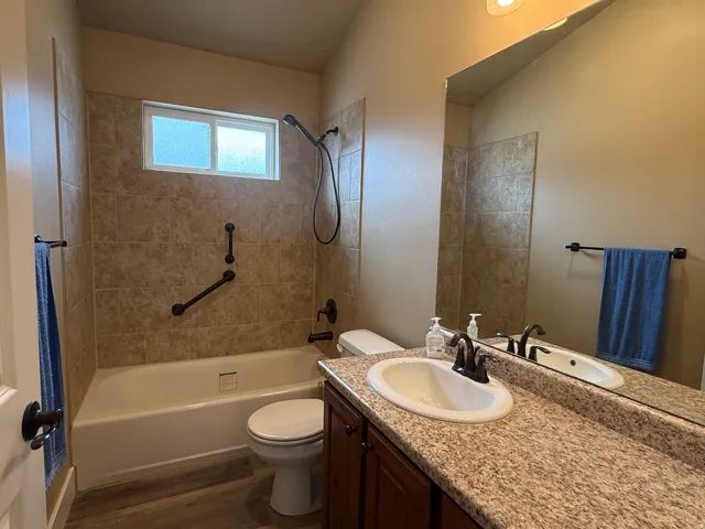 Full bath with vanity, washtub / shower combination, and dark wood finished floors