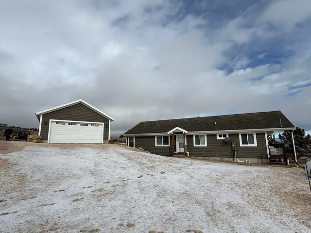 Single story home featuring an outdoor structure, a garage, roof with shingles, and driveway