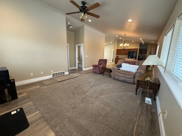Living room featuring hanging lights, ceiling fan, dark wood finished floors, and vaulted ceiling