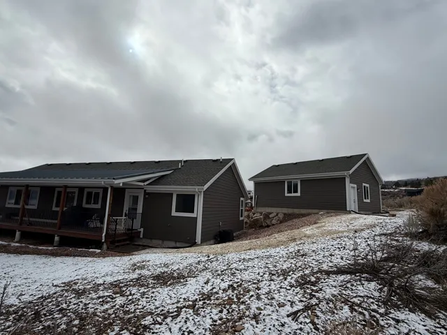 Snow covered rear of property with a wooden deck and a shingled roof