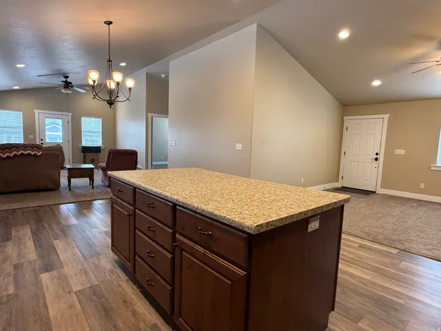 Kitchen with open floor plan, ceiling fan, lofted ceiling, and dark wood finish cabinetry