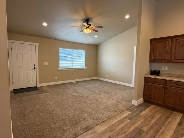Unfurnished living room featuring a ceiling fan, vaulted ceiling, dark wood-style floors, dark colored carpet, and recessed lighting