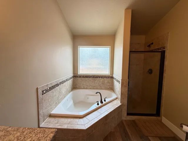 Bathroom featuring a tub with jets, a shower stall, and wood finished floors