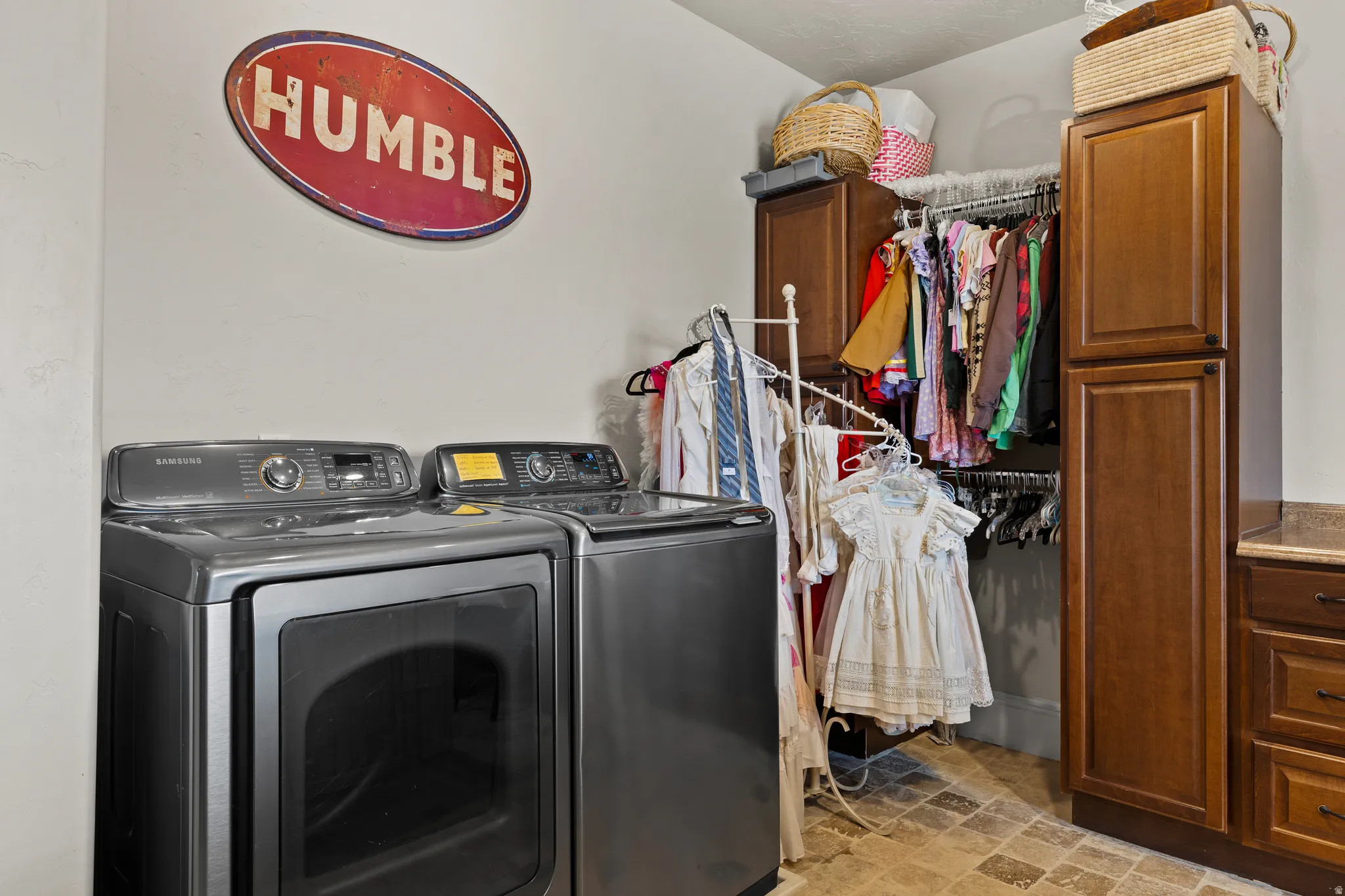 Laundry area with cabinet space, washer and clothes dryer, and light stone finish floors