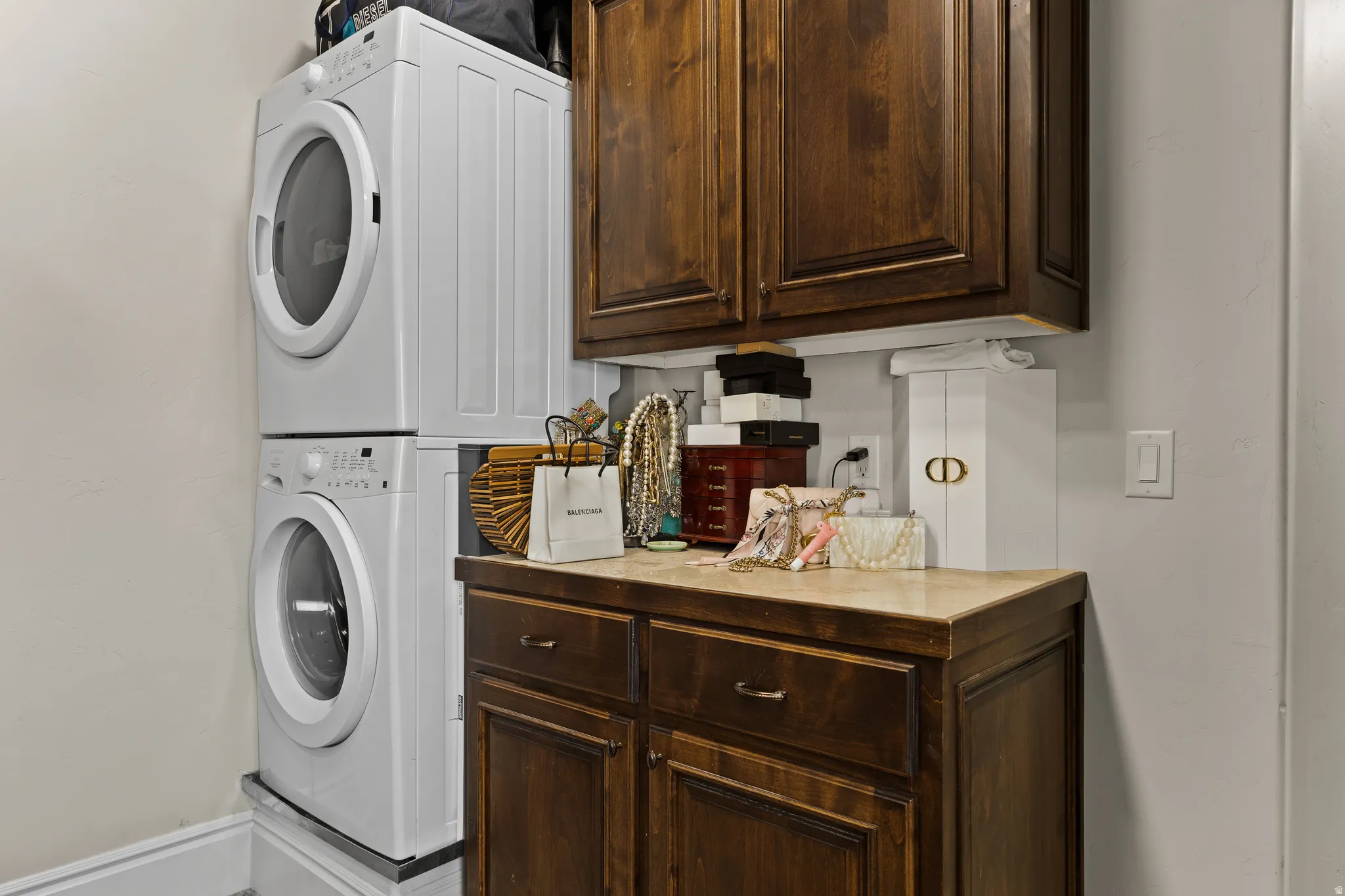 Laundry area featuring stacked washer / dryer and cabinet space