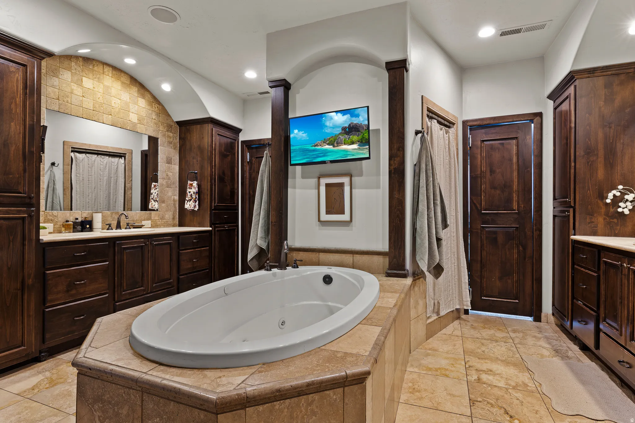Bathroom featuring vanity, a jetted tub, and recessed lighting