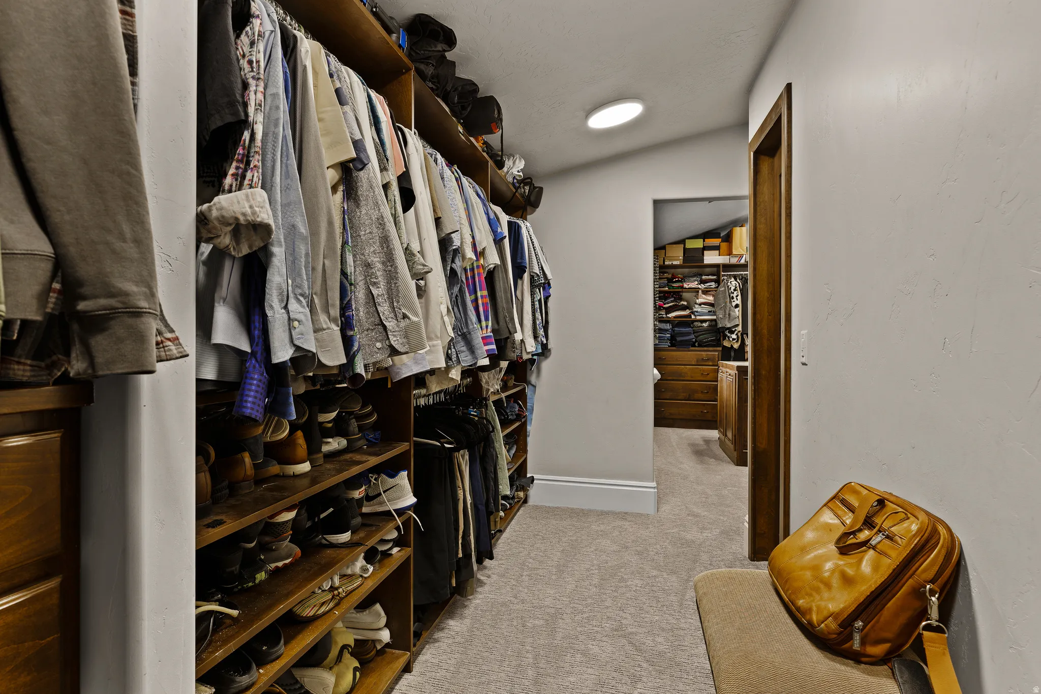 Walk in closet featuring light carpet and vaulted ceiling
