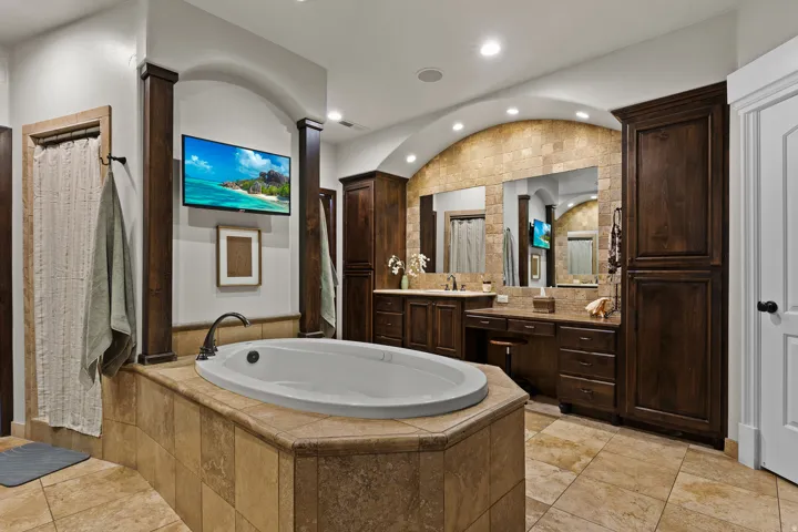 Bathroom with vanity, a bath, vaulted ceiling, and recessed lighting