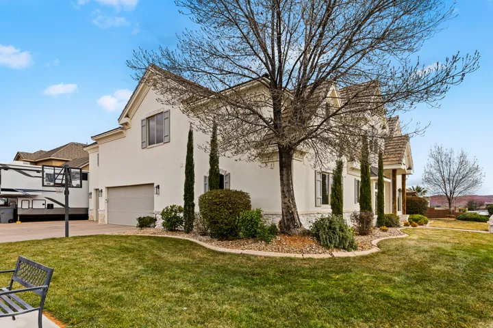 View of home's exterior with stucco siding, a garage, a lawn, and driveway