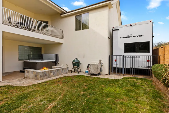 Rear view of house with a balcony, a patio area, stucco siding, and an outdoor fire pit