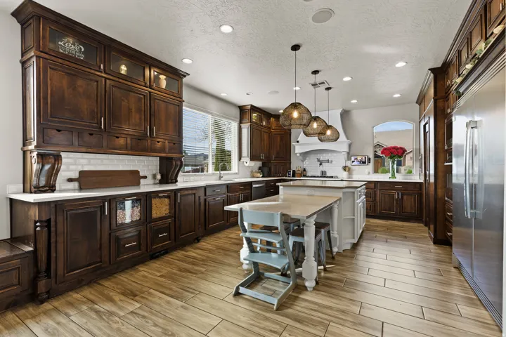 Two tone kitchen featuring a kitchen bar, pendant lighting, stainless steel appliances, tasteful backsplash, and wood finish floors