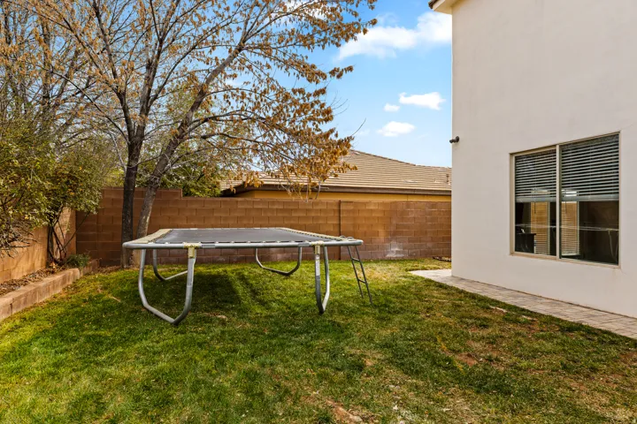 Fenced backyard with a trampoline and a patio