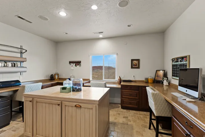 Office with built in desk, light stone finish floors, a textured ceiling, and recessed lighting