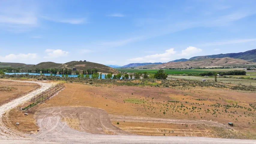 Expansive open land featuring a gravel path, natural vegetation, and distant water