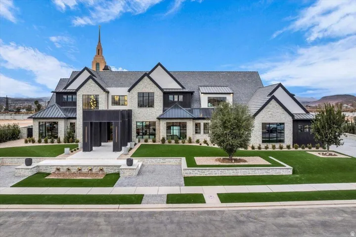 View of front of house featuring a standing seam roof, a front lawn, and stone siding
