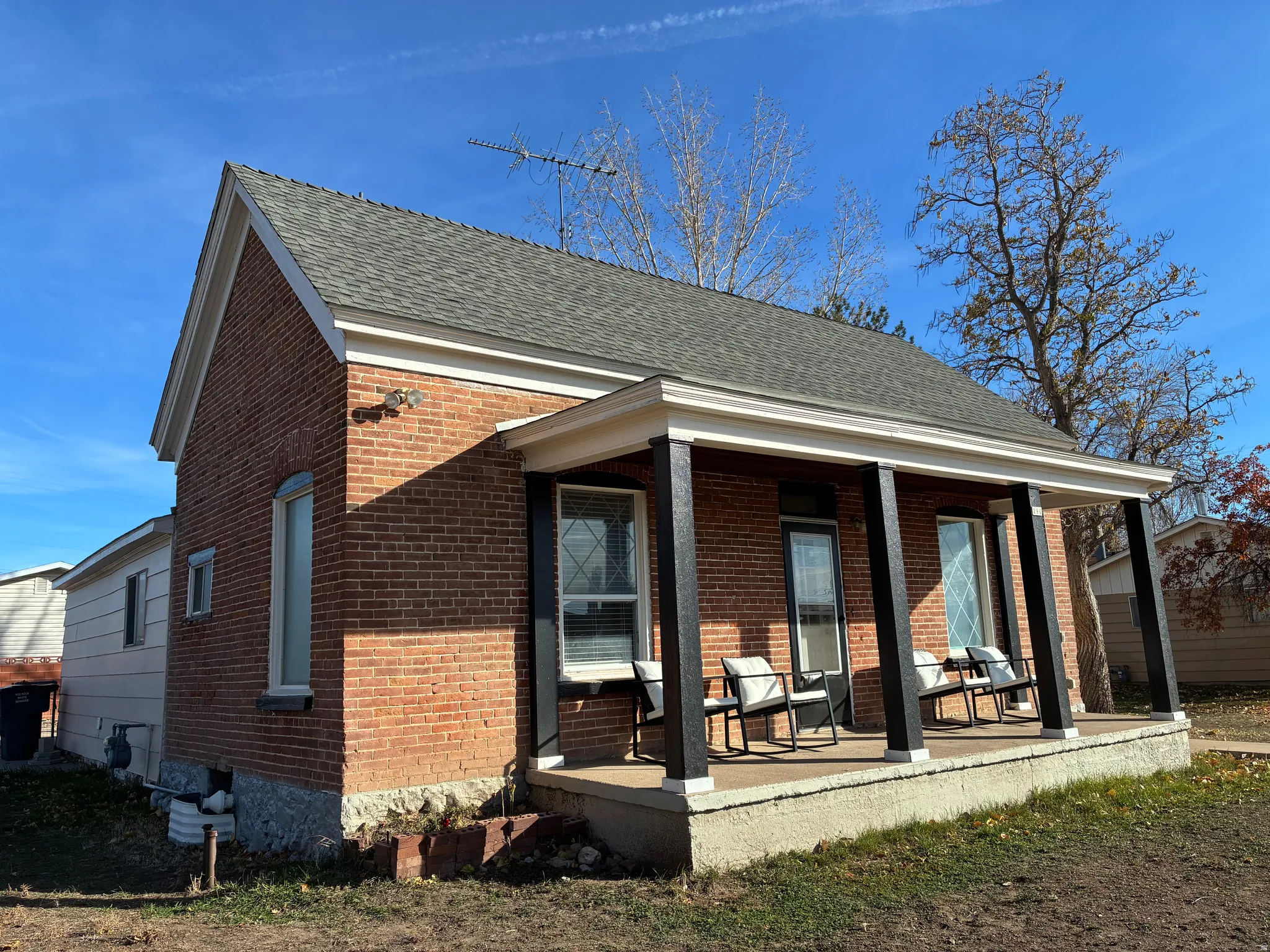 Front view of property with brick siding, covered porch, and a shingled roof