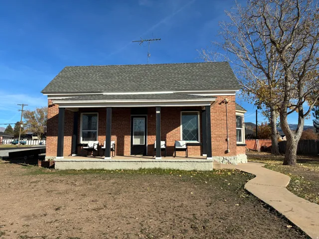 Front of house with covered porch, brick siding, and a shingled roof
