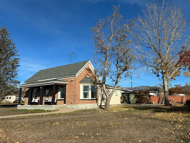 View of home's exterior with covered porch, brick siding, and a shingled roof