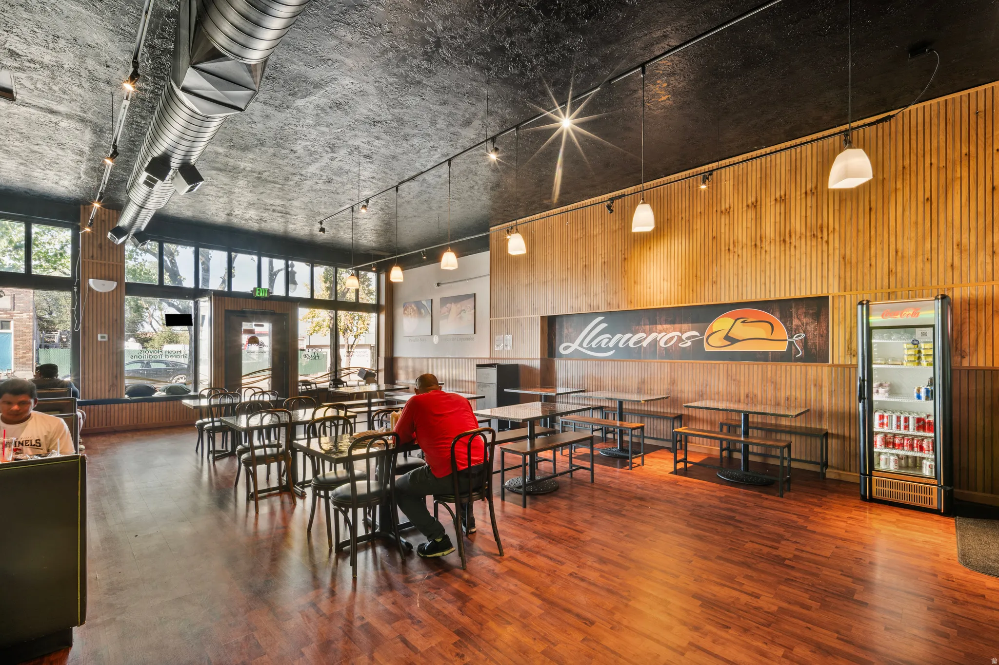 Dining room with wood walls, wood finished floors, rail lighting, and a high ceiling