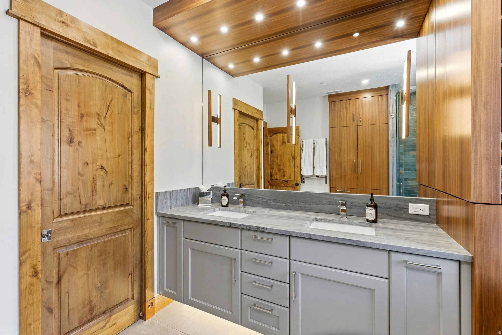Dual vanity with light gray cabinetry, integrated sinks, and stone countertops