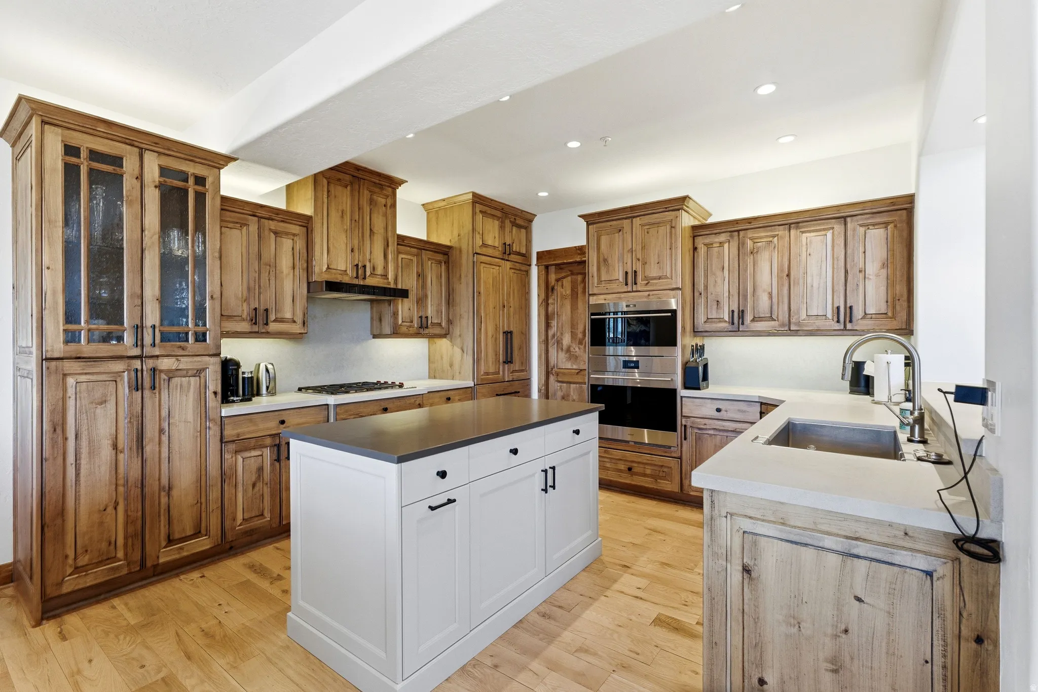 Kitchen featuring light wood-finish flooring, light wood cabinetry, and a white center island with a dark countertop