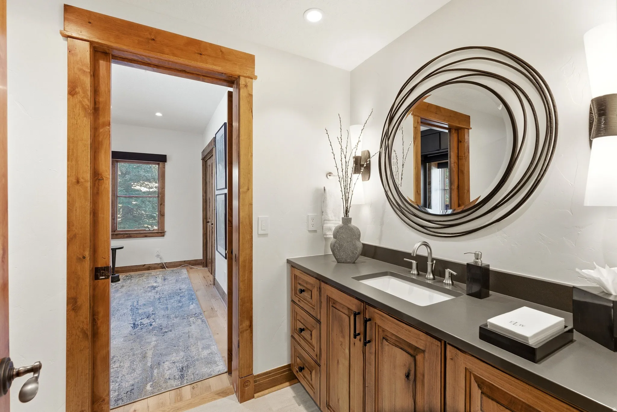 Bathroom vanity featuring a single undermount sink, dark countertop, and wood-finish cabinetry