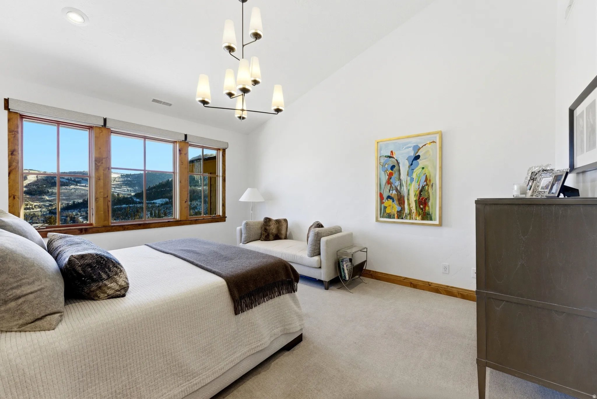 Vaulted ceiling bedroom featuring large windows with wood trim, a contemporary chandelier, recessed lighting, and light-toned carpeting
