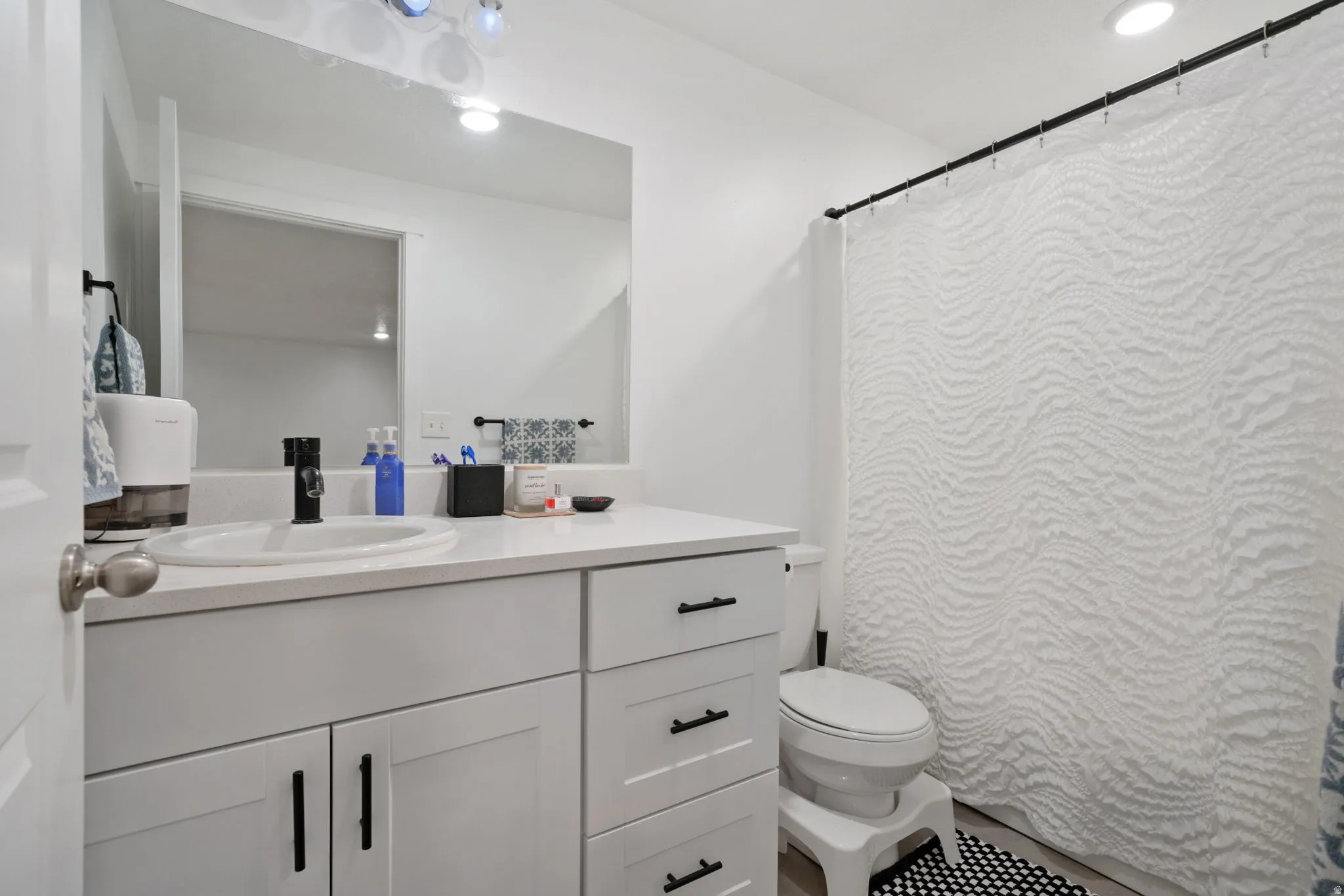 Bathroom with vanity, a shower with shower curtain, and recessed lighting