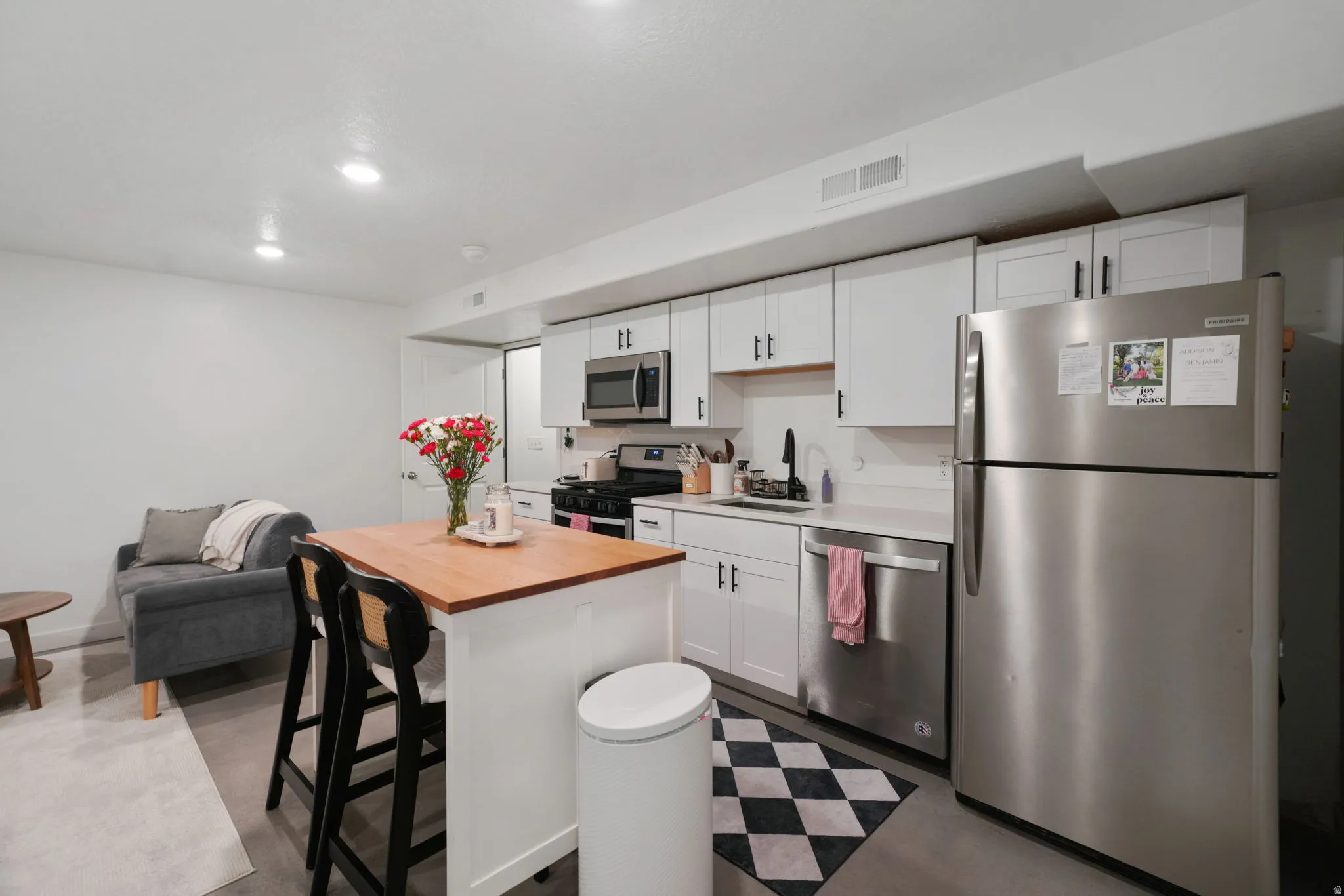 Kitchen with stainless steel appliances, white cabinets, a kitchen bar, dark floors, and recessed lighting