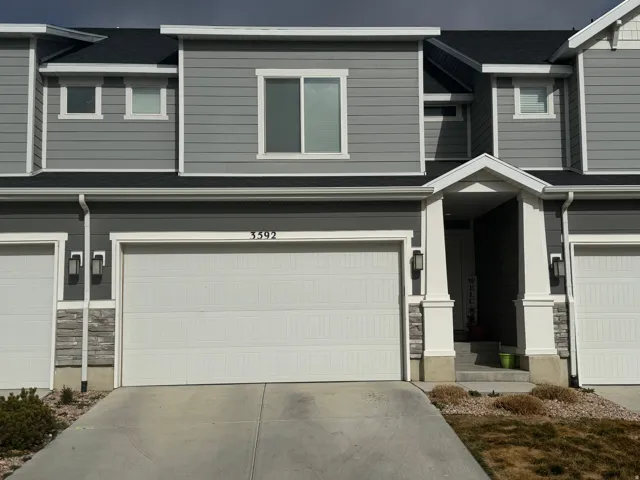 View of front of property featuring stone siding, a garage, concrete driveway, and a shingled roof