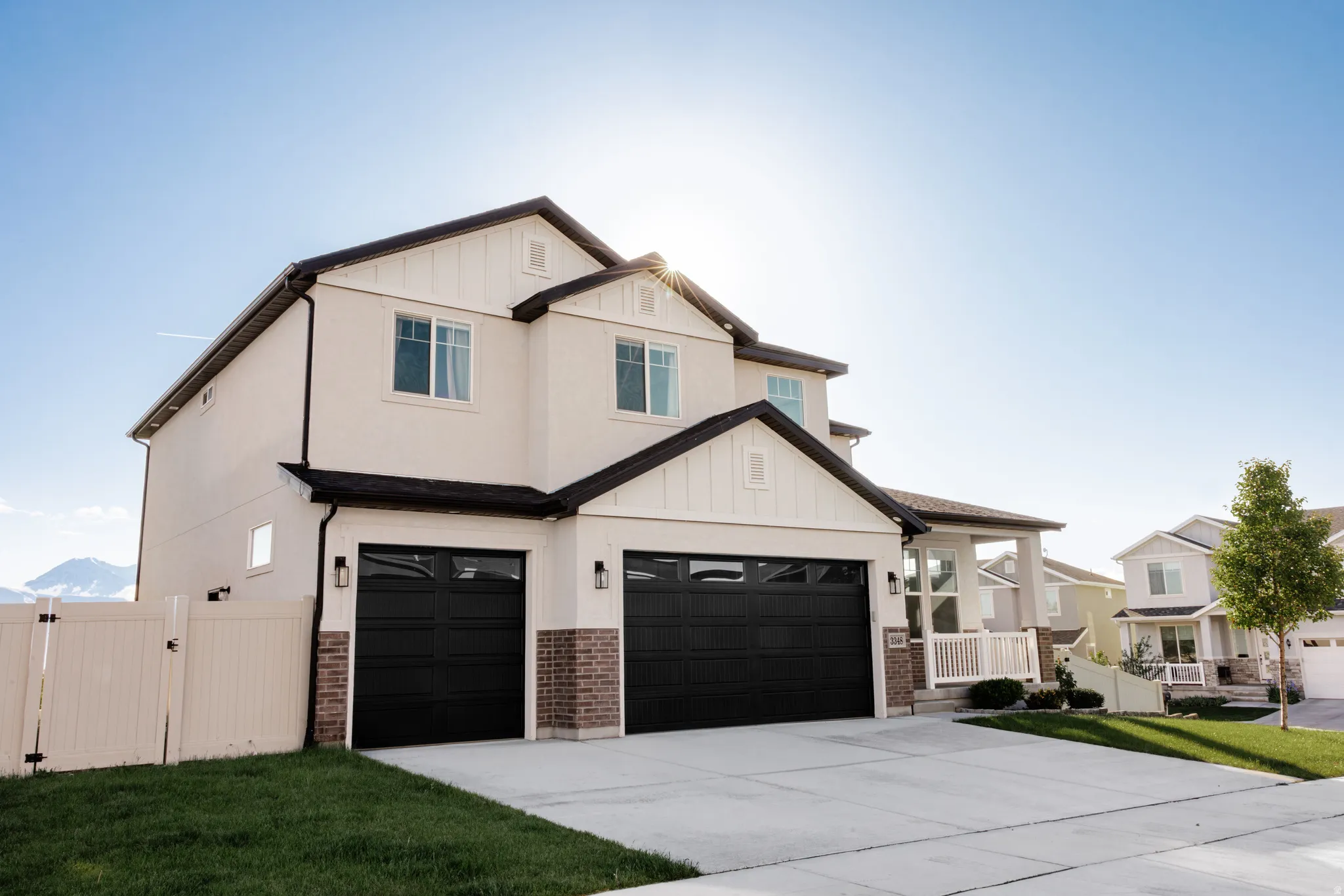 Two-story residence featuring a cream-colored stucco exterior with dark trim accents and white window frames