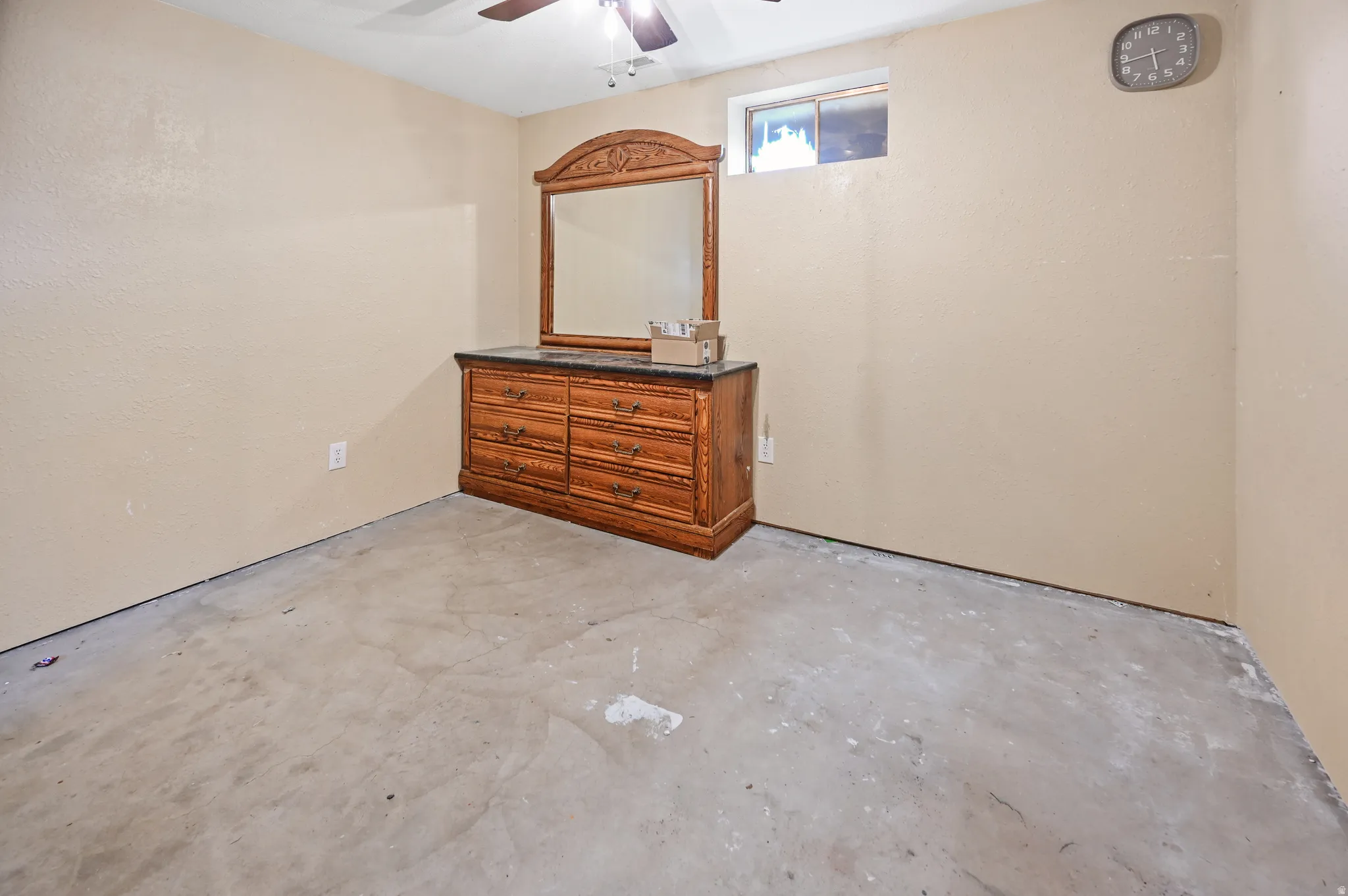 Unfurnished room with unfinished concrete flooring and a ceiling fan