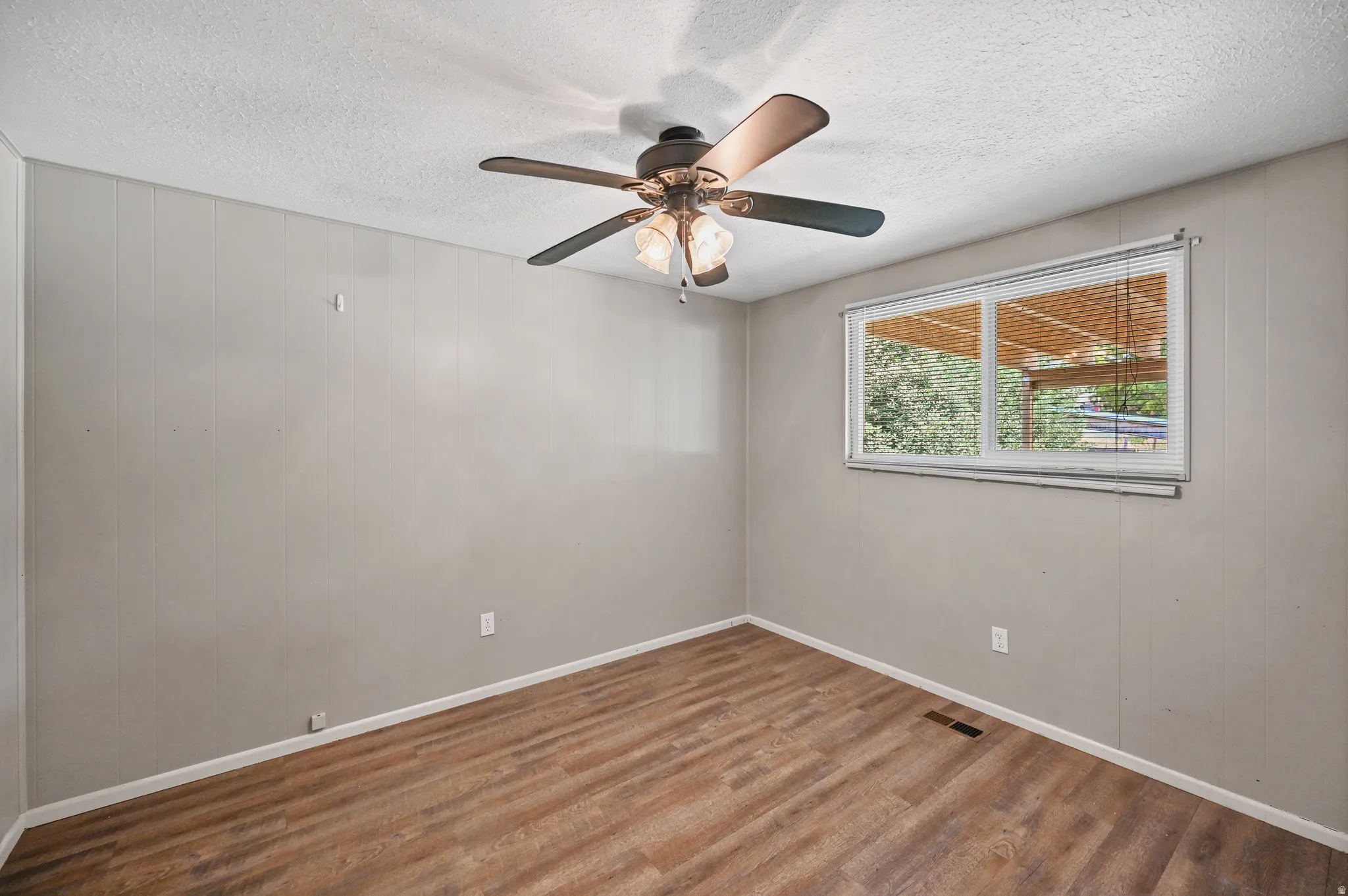 Unfurnished room with ceiling fan, a textured ceiling, and wood finished floors