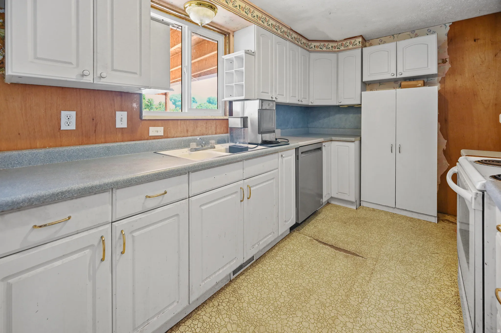 Kitchen featuring light flooring, white cabinets, dishwasher, white electric range, and light countertops